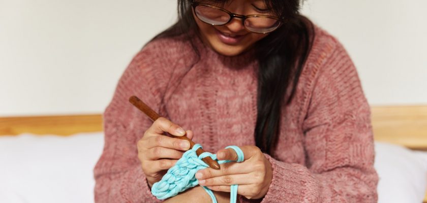 girl with glasses is knitting clothes