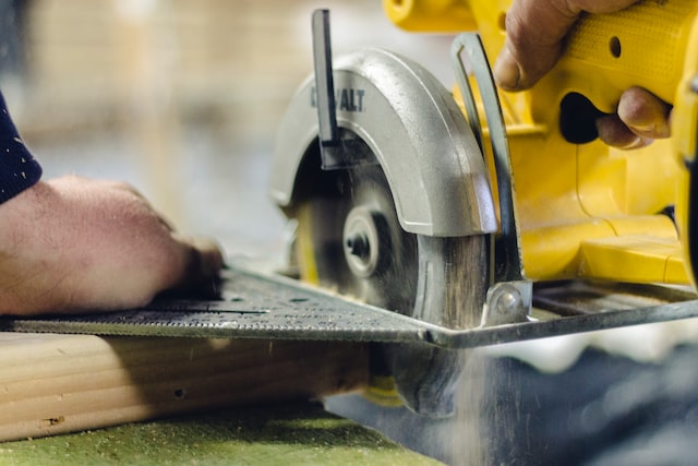 man cutting wood with a tool