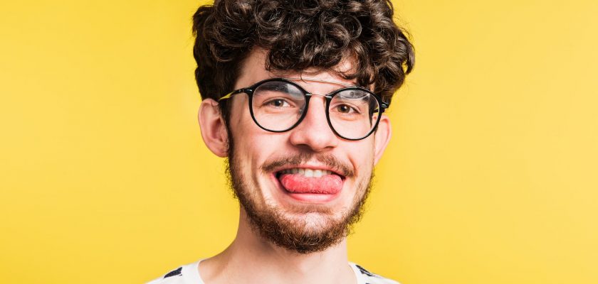 man shows his tongue on a yellow background